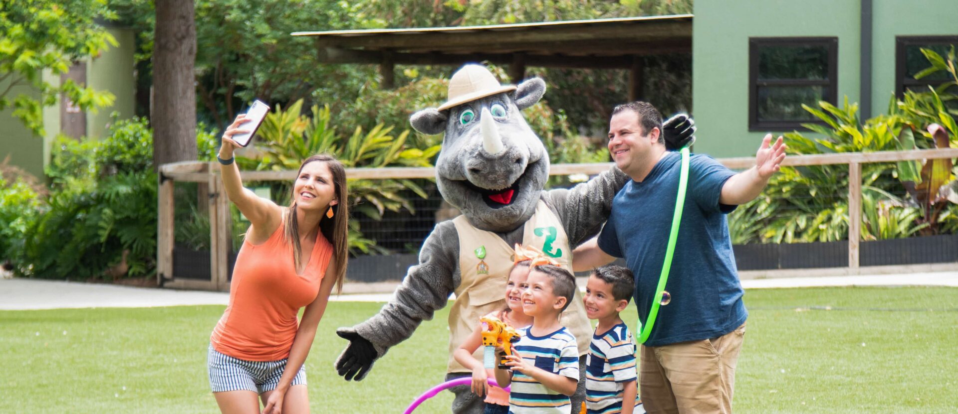 A family at the zoo posing with a rhino mascot