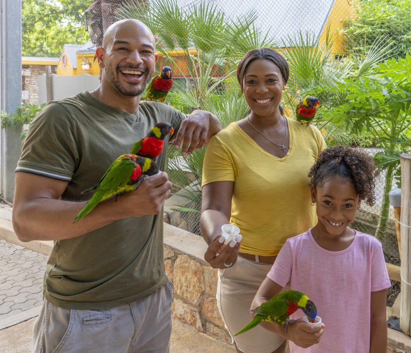 Family of three posing with parakeets