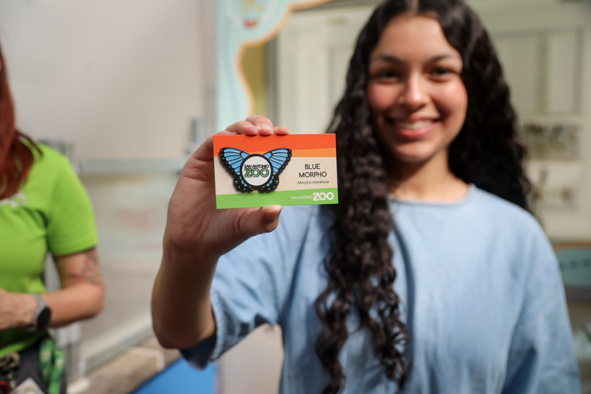 girl holding up a san antonio zoo blue morpho card